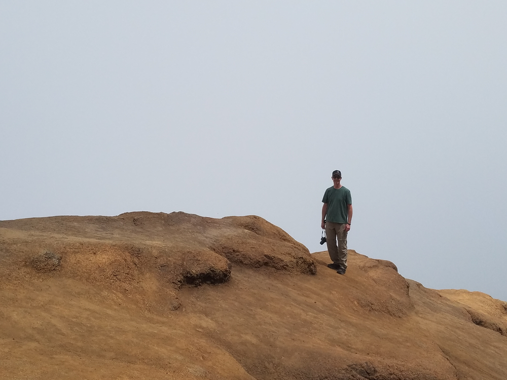 The author's husband standing at the overlook for the Waimea Canyon as a cloud rolls in.